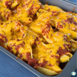 Close-up of baked taco stuffed shells in a casserole dish, topped with salsa and melted Tex-Mex cheese, showing the cheesy, saucy pasta shells ready to serve.