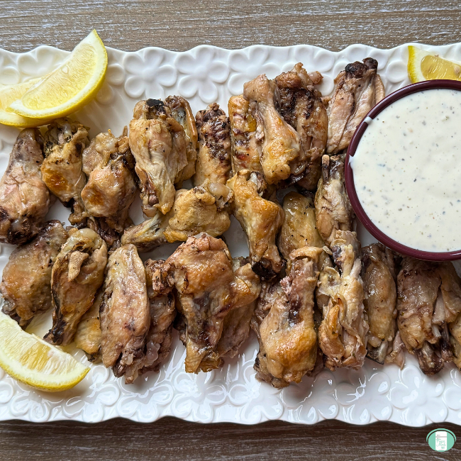 Cooked Lemon Pepper Chicken Wings on white platter with lemons