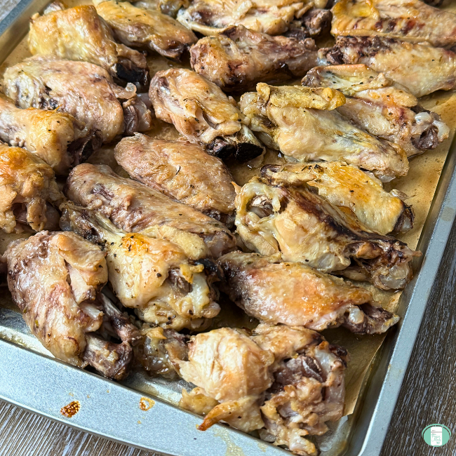 Baked chicken wings and chicken drum sticks on baking sheet