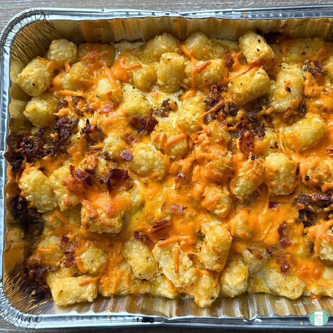 Baked Breakfast Tater Tots in casserole dish with cheese, bacon and sausage bits.