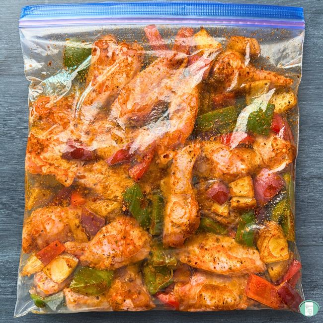 Cajun roast chicken with vegetables and potatoes with sauce in plastic freezer bag. 