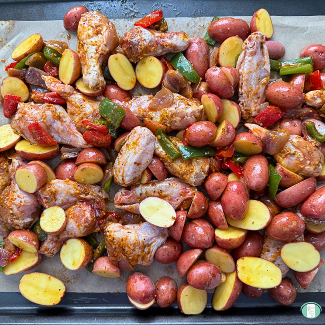 Chicken, potatoes and vegetables with sauce on parchment paper.