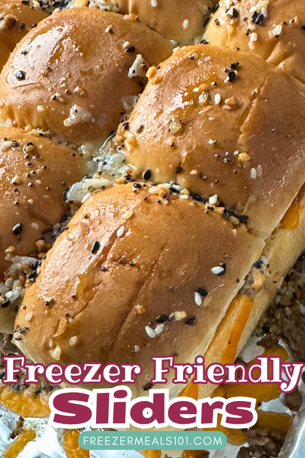 buns filled with ground beef and cheese topped with melted butter and sesame seeds in a foil tray