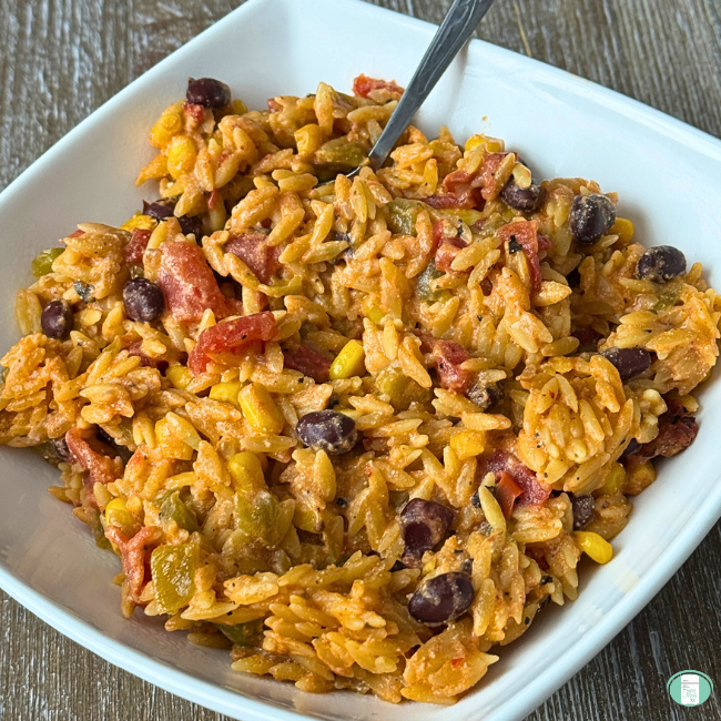 Enchilada Orzo casserole with beans, tomatoes, beans in white dish.