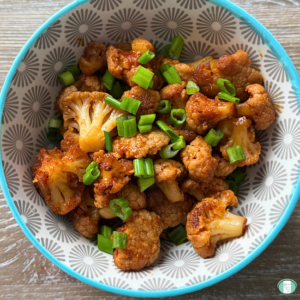seasoned cauliflower in a bowl topped with sliced green onions