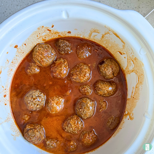 Meatballs and sauce in white bowl.