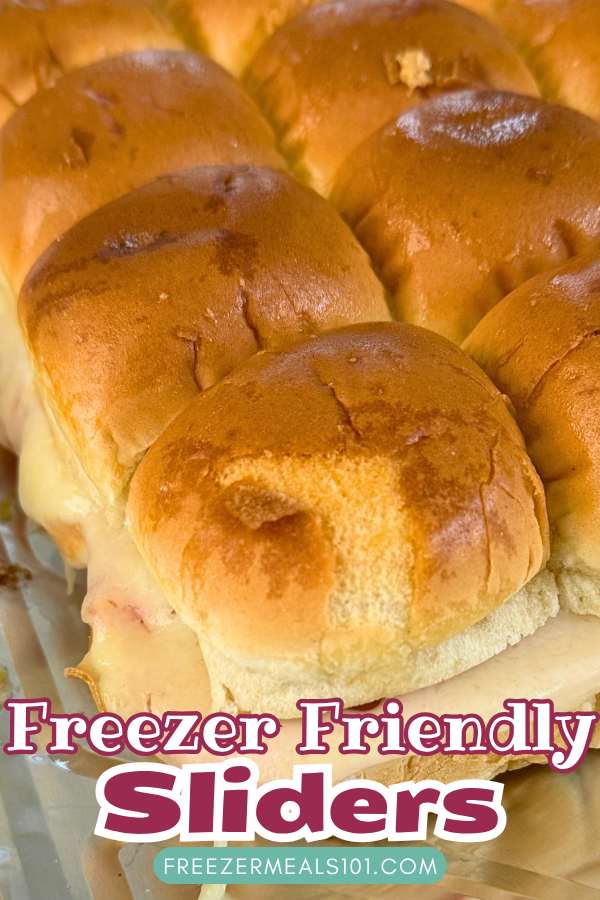 slider buns filled with meat and melted cheese in a foil tray