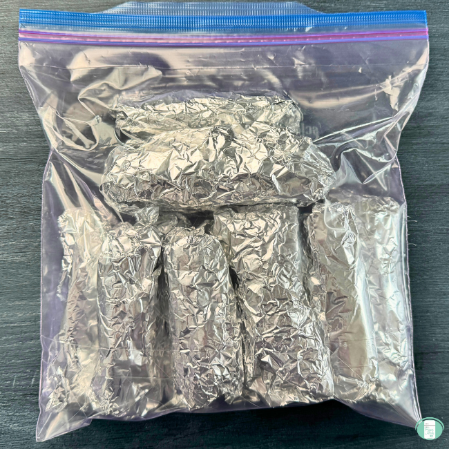 Burritos wrapped in foil in a freezer bag.
