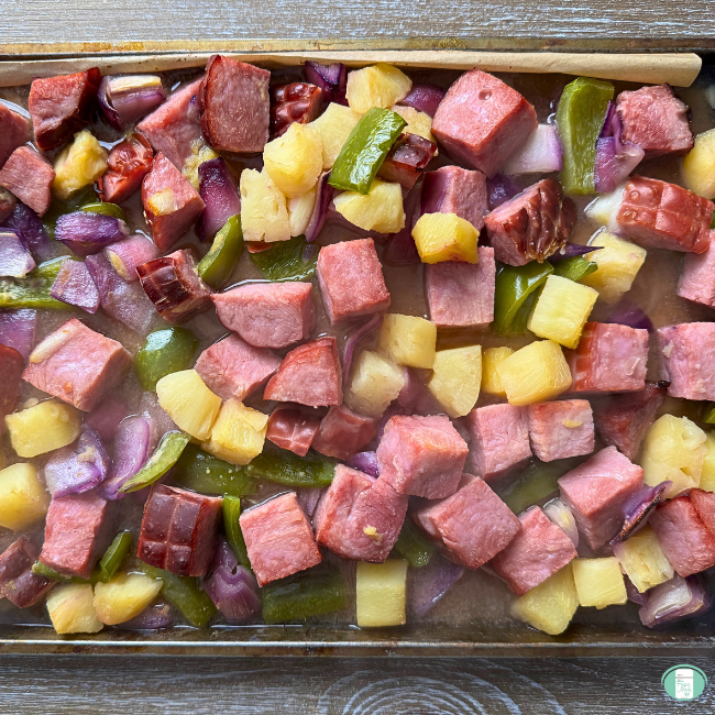 Ham, green pepper, purple onions and pineapple on baking sheet.
