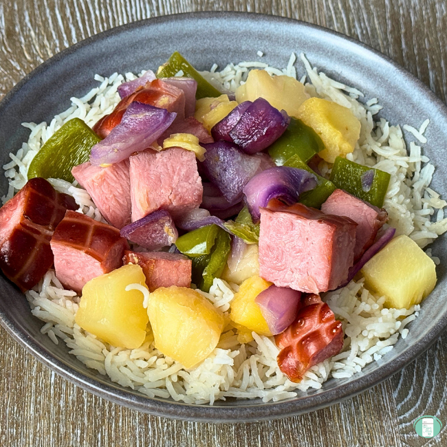 Cooked ham, green pepper, purple onion and pineapple served with rice in bowl.