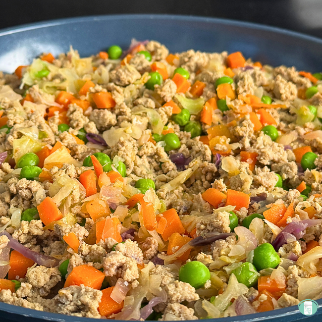 Ground turkey, carrots, peas, onions cooking in frying pan.
