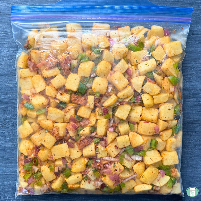 Breakfast hash in a ziploc freezer bag, with potato cubes, bacon, onion, peppers, and seasonings