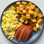 Make-ahead breakfast hash with potatoes, bacon, onions, and green peppers served with apple slices and scrambled eggs
