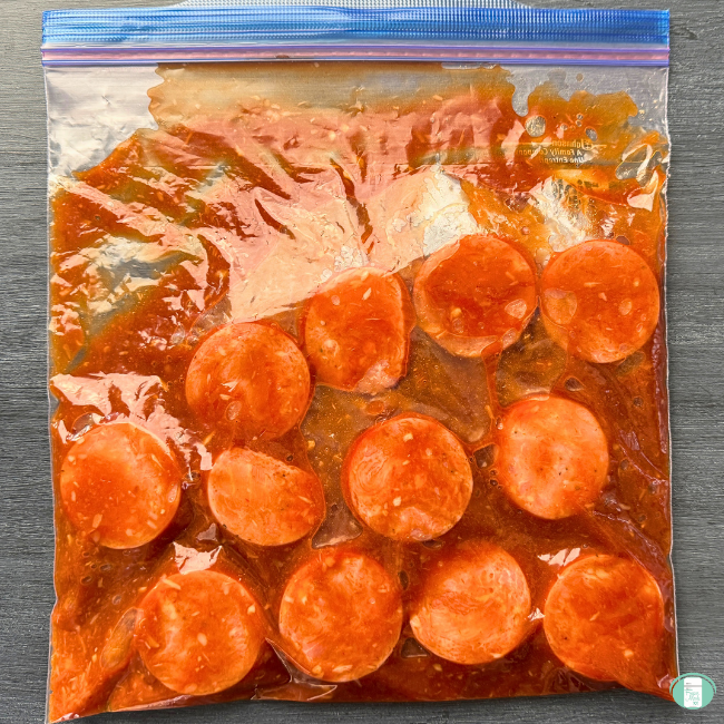 Cut up kielbasa with an orange sauce in a ziploc bag for the freezer