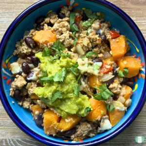Turkey sweet potato skillet served in a bowl with avocado and cilantro on top