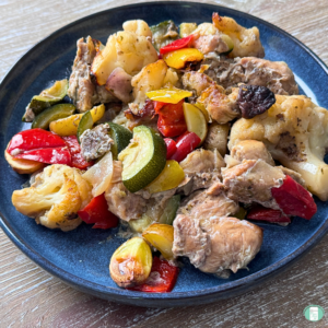 Freezer meal chicken sausage and vegetable sheet pan dinner, served on a blue plate