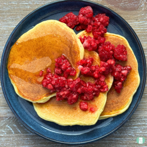 Freezer friendly, high protein cottage cheese pancakes, served on a plate with a raspberry sauce and maple syrup