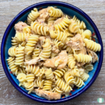 Slow cooker cajun chicken alfredo served on pasta in a blue bowl