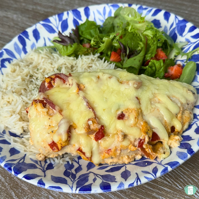 Make ahead smothered chicken bake with red sauce and cheese served on a blue and white plate with salad and rice