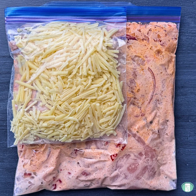 A bag of shredded cheese stapled to a bag of smothered chicken bake freezer meal, ready to freeze