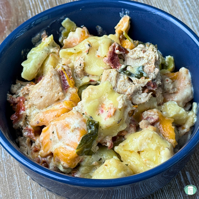 Creamy crockpot tuscan chicken tortellini served in a bowl with spinach, tortellini, tomatoes, cheese