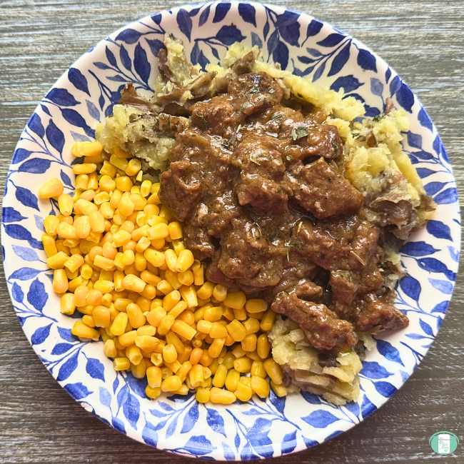 Freezer meal to slow cooker steak bites served over mashed potatoes with a side of corn