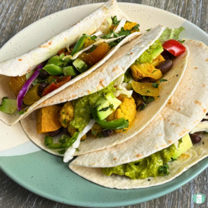 Freezer meal roasted veggie tacos served in tortillas with avocado, veggies, cilantro, and more